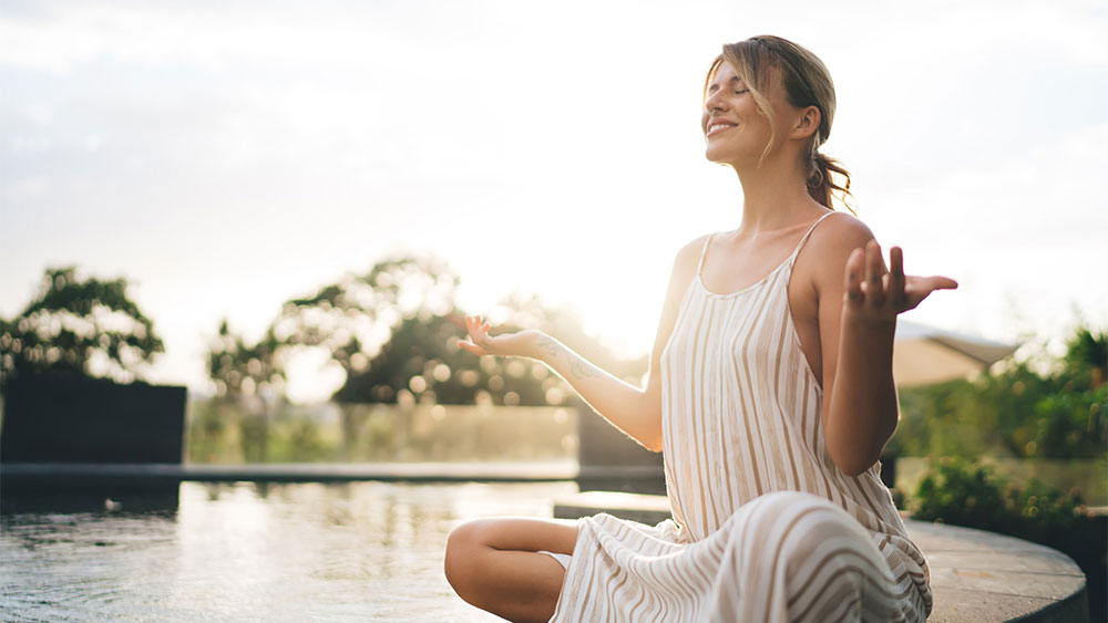 Mulher praticando meditação ao ar livre, representando equilíbrio emocional e autocuidado na adaptação ao mudar de país.