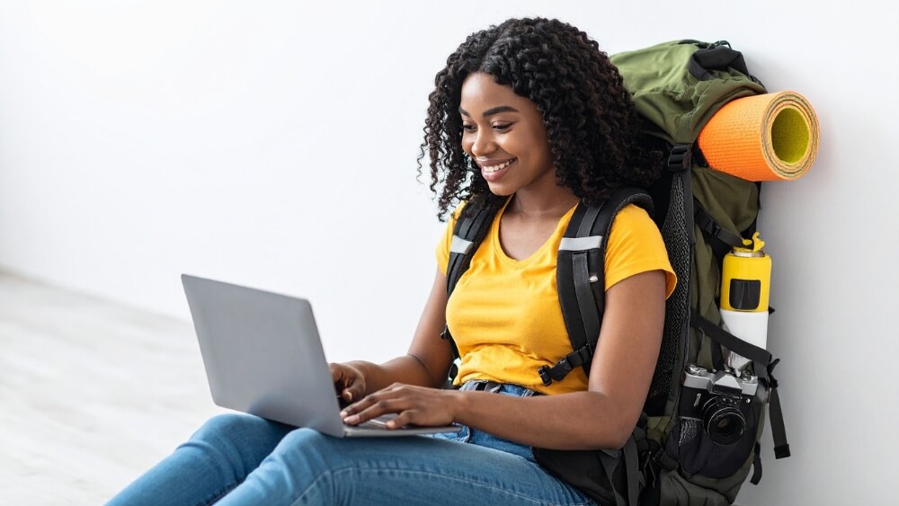 Nômade digital com mochila usando laptop, representando os desafios da reconstrução do pertencimento